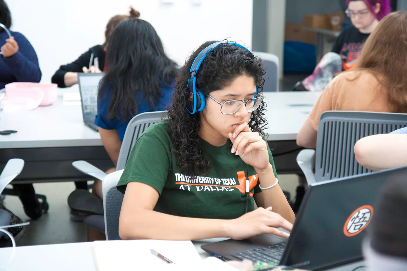 Student wearing blue headphones while studying on a laptop.